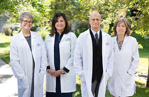 Four physicians pose for the camera in their white lab coats.