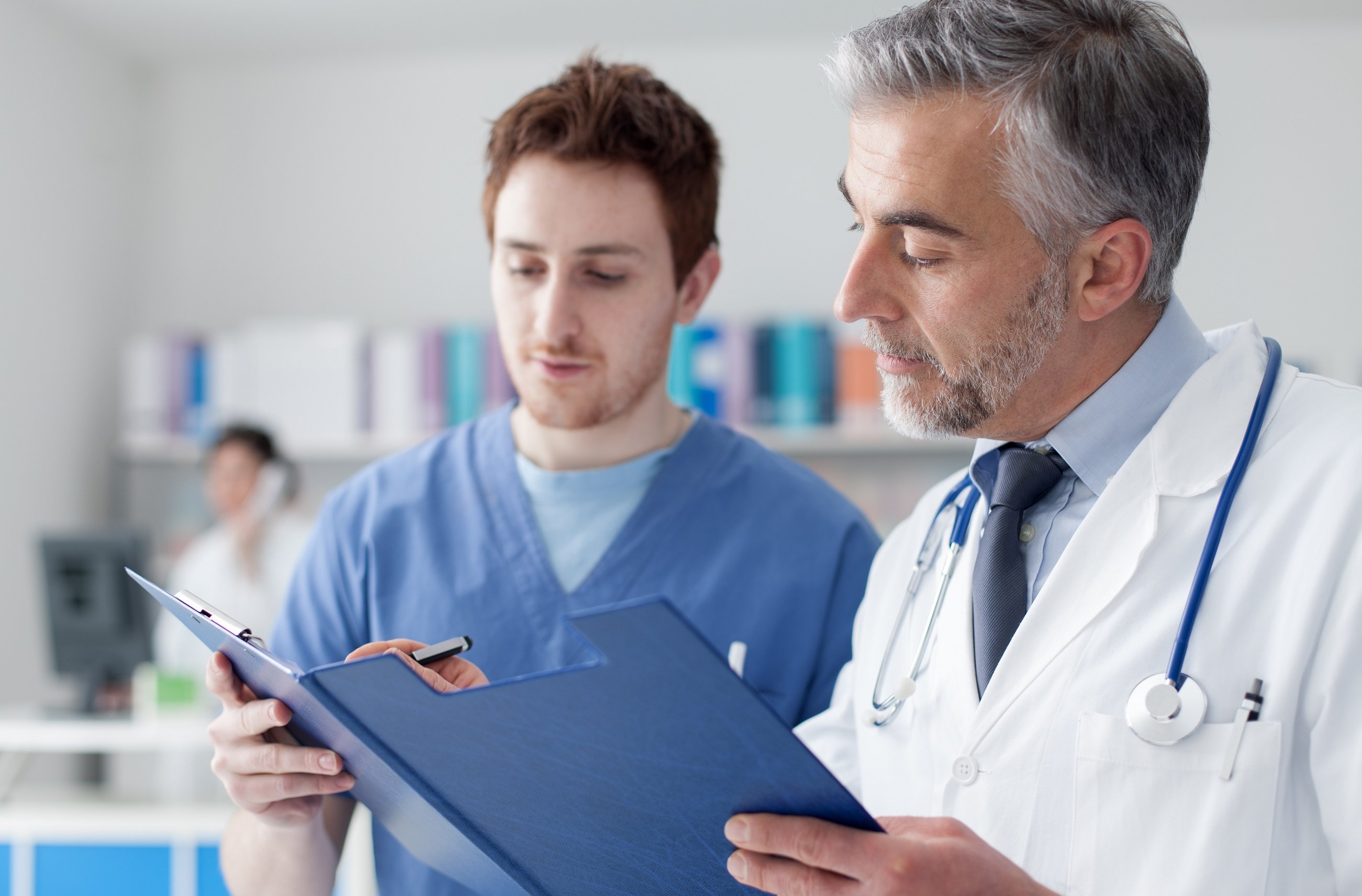 Doctor and practitioner examining patients medical records on a clipboard