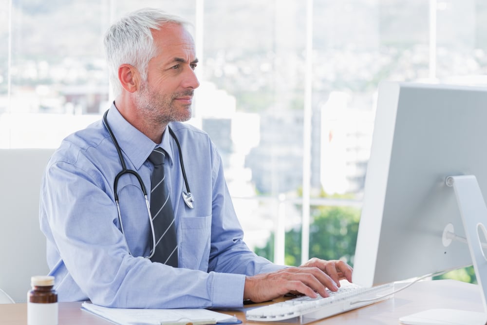 Médico tecleando en su ordenador en la consulta-1