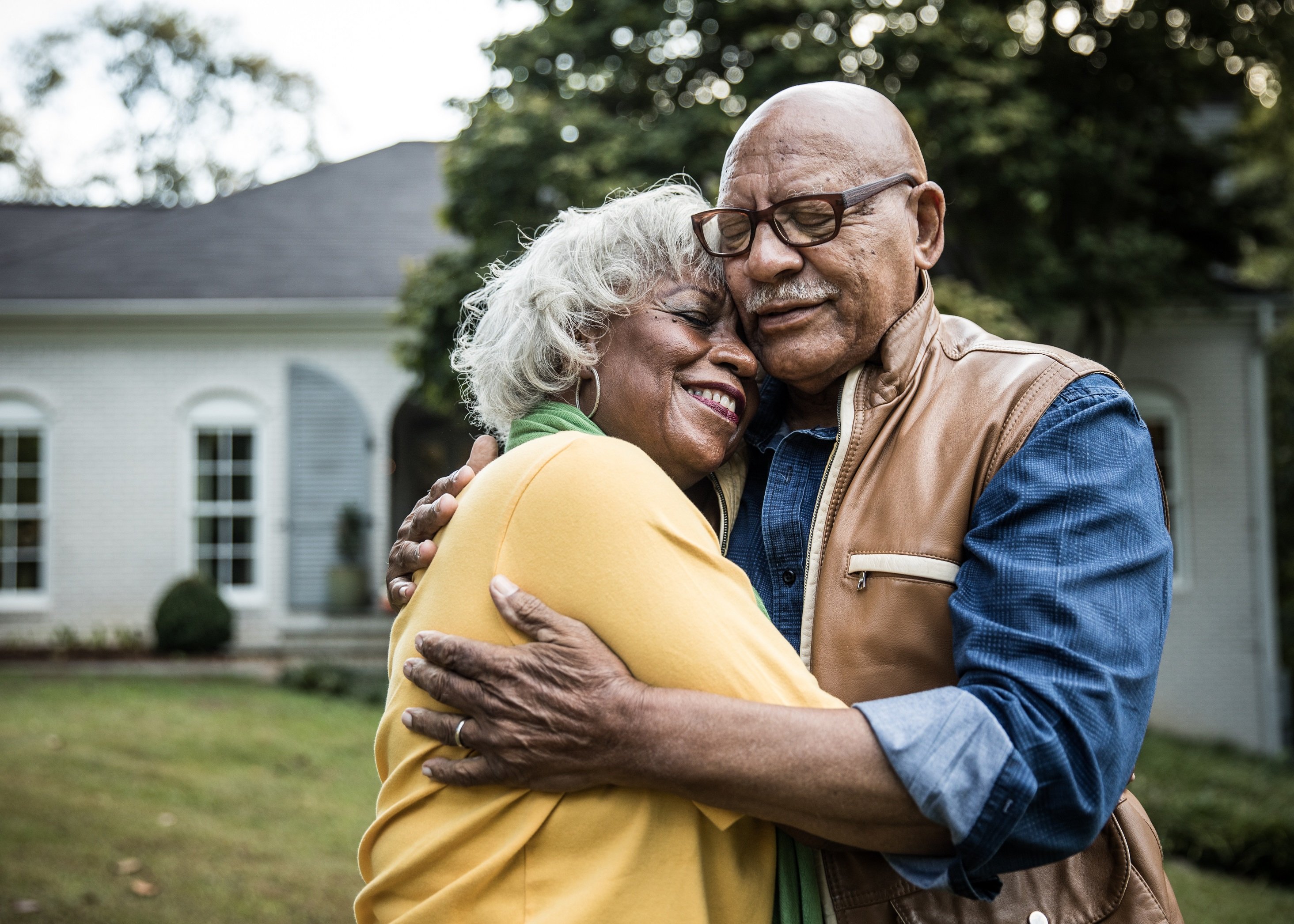 happy couple standing outside their home and hugging