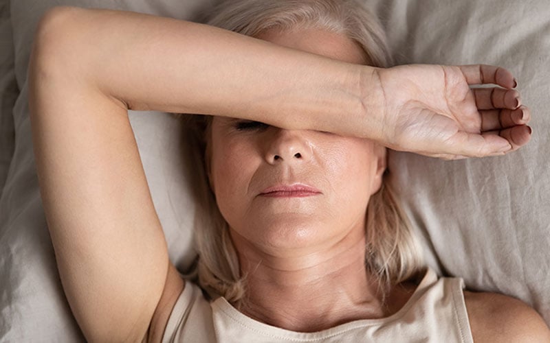 mujer cansada y tumbada en la cama