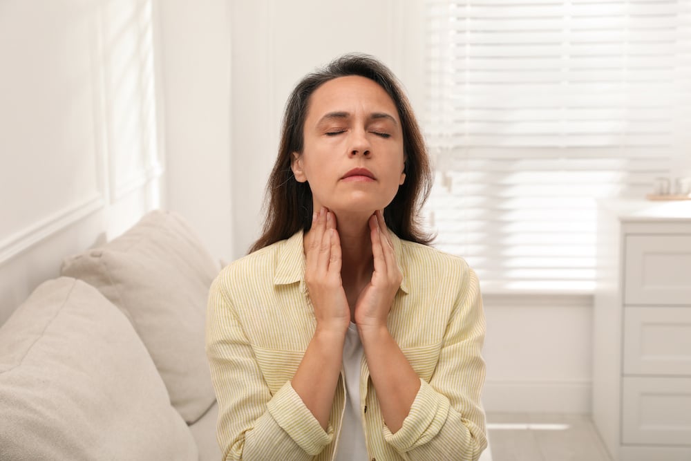 A woman feels the lymph nodes in her beck.