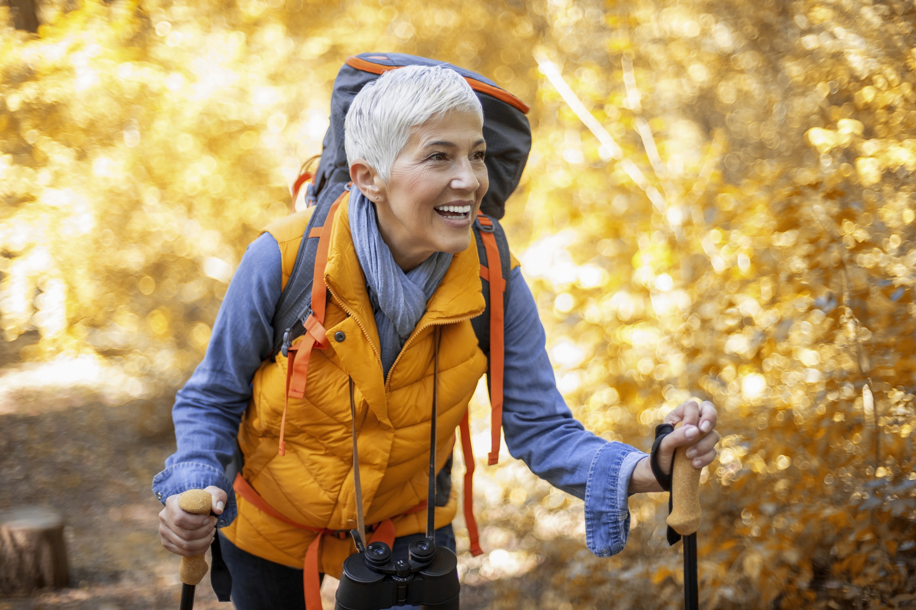 Mujer mayor haciendo senderismo en un bosque otoñal